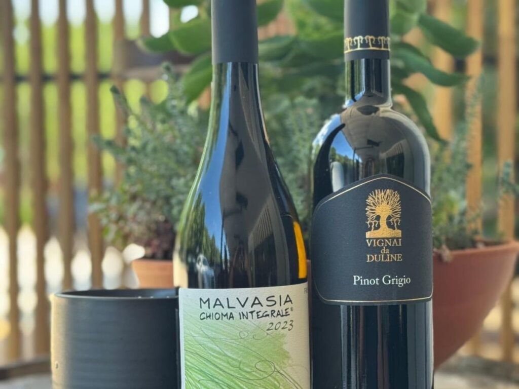 Winemaker pouring a glass of white wine at a rustic farmhouse tasting table.