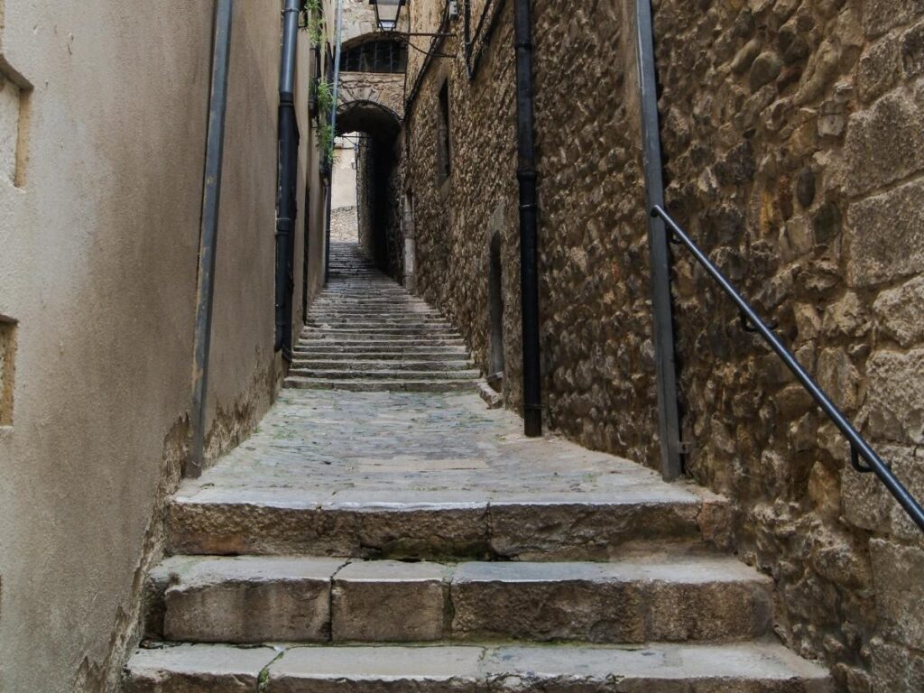 Steep cobbled alley with stone steps in a hill town, showing why sturdy shoes are recommended