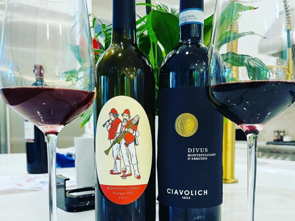 A glass of deep ruby Montepulciano d’Abruzzo being poured beside grilled lamb skewers