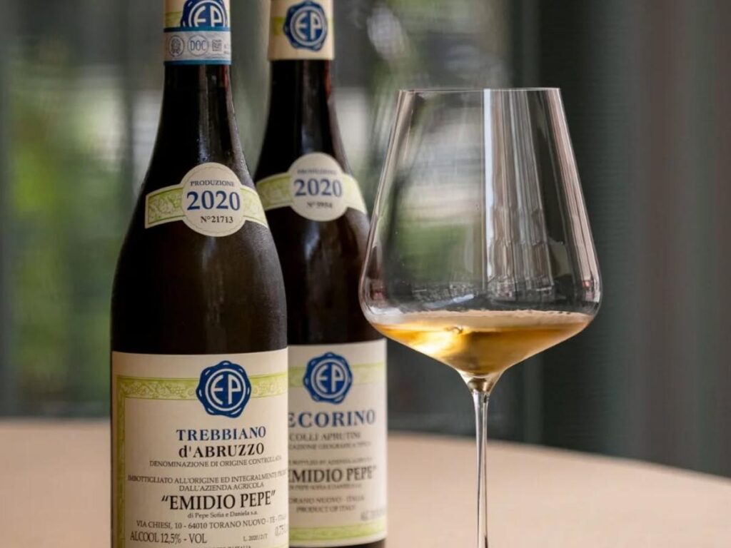 Small family-run winery tasting with bottles on the table, a winemaker pouring glasses and simple plates of local salumi.