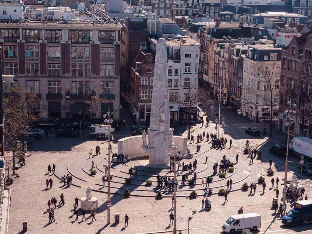 Early morning view of Dam Square in Amsterdam with the Royal Palace and cyclists passing through