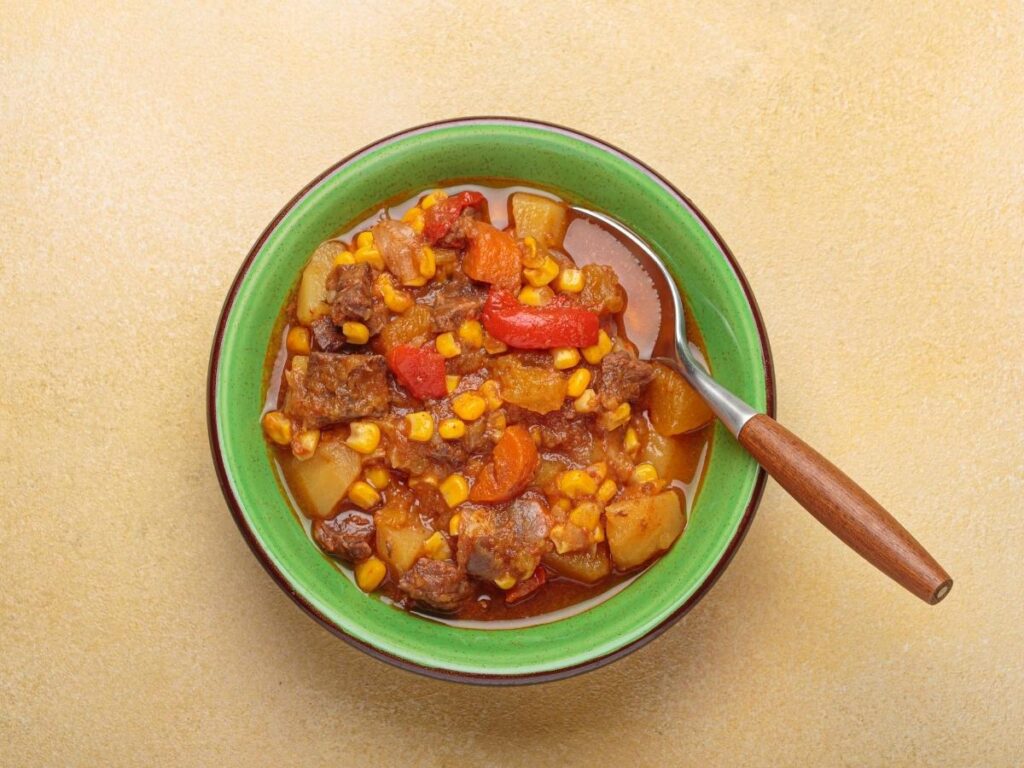 Beef carbonada stew simmered in red wine, served with polenta on a wooden table in a mountain trattoria.