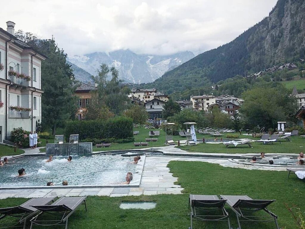 Outdoor thermal pools at Pré Saint Didier steaming in winter with snowy mountains beyond.