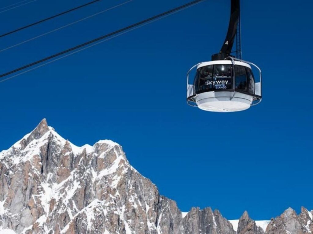 Rotating glass cabin of the Skyway Monte Bianco climbing toward Pointe Helbronner with glaciers below.