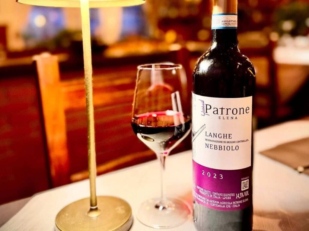 Glasses of red Nebbiolo wine on a wooden barrel overlooking vineyards in the Aosta Valley.