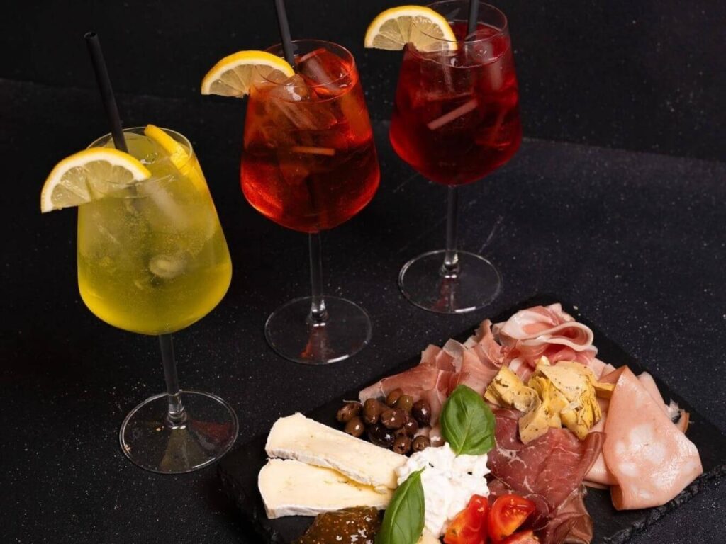 “Glasses of Aperol Spritz and wine during aperitivo hour in Piazza delle Erbe, Verona.”