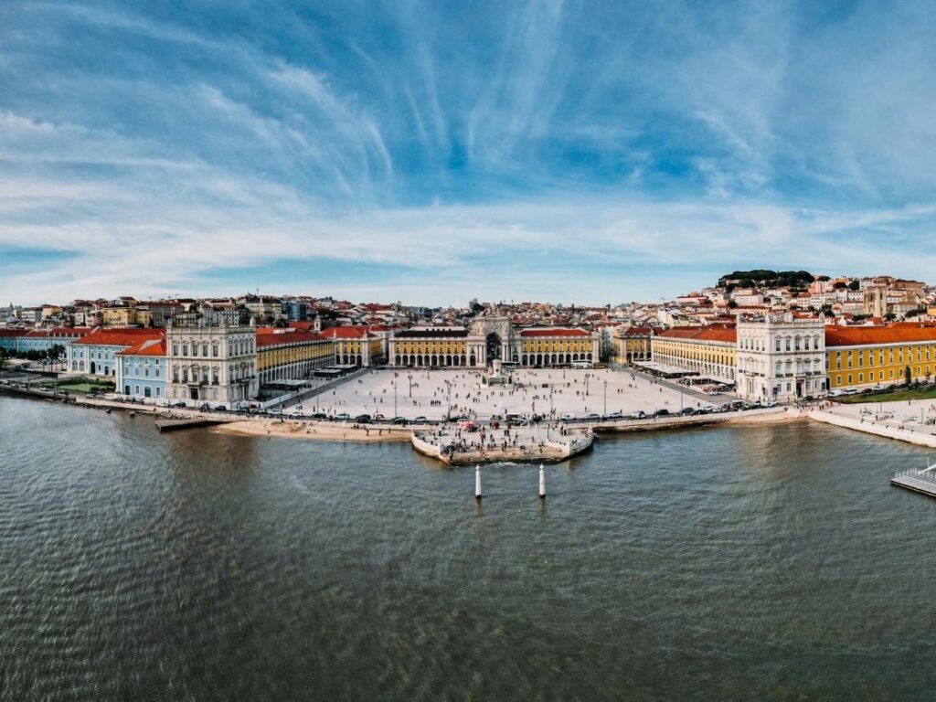 Praça do Comércio opening onto the Tagus river with people walking across the square