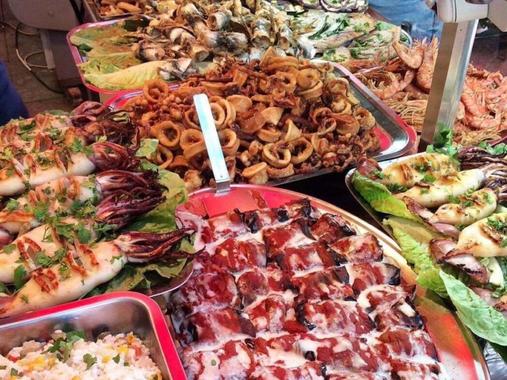 Busy Ballarò Market with vendors cooking panelle and locals eating street food in Palermo