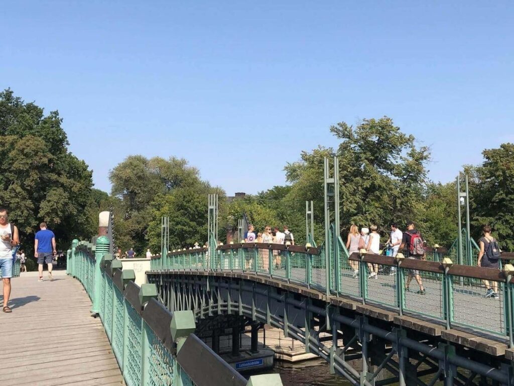 Early morning sunlight filtering through trees in Tiergarten park with people walking and cycling