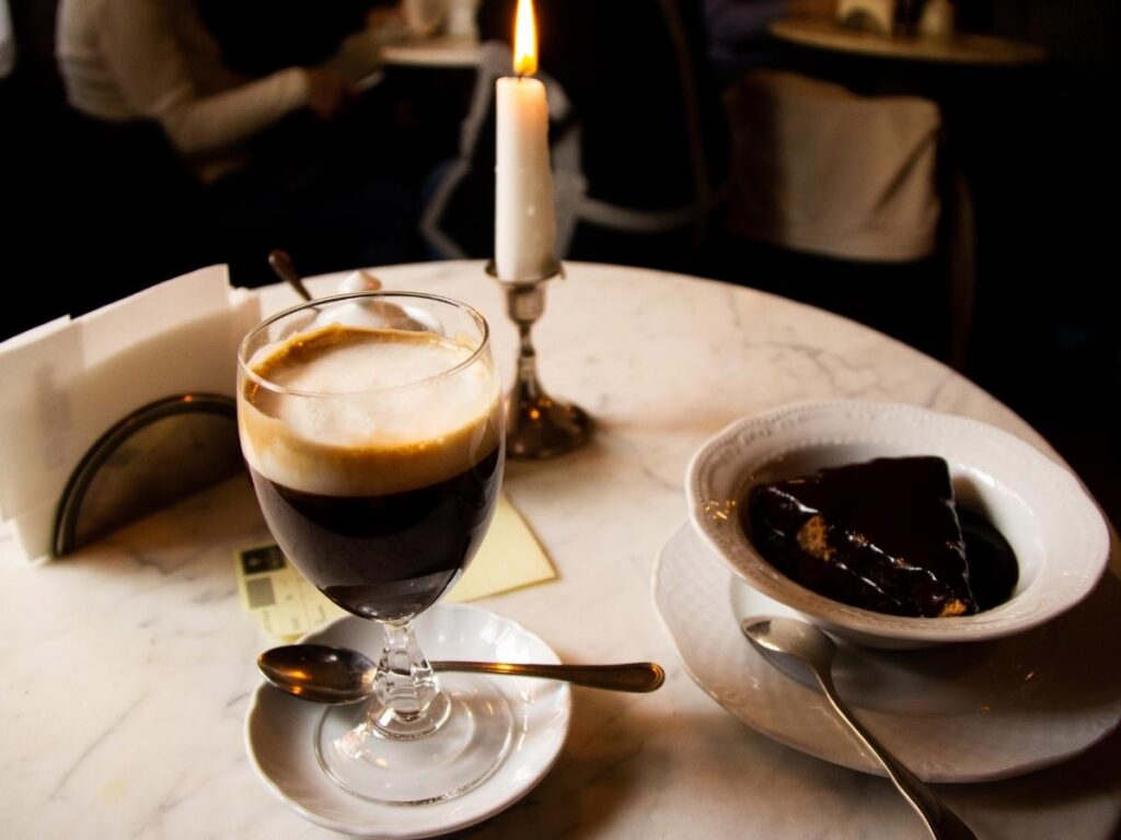 A steaming glass of bicerin on a saucer inside Caffè Al Bicerin.