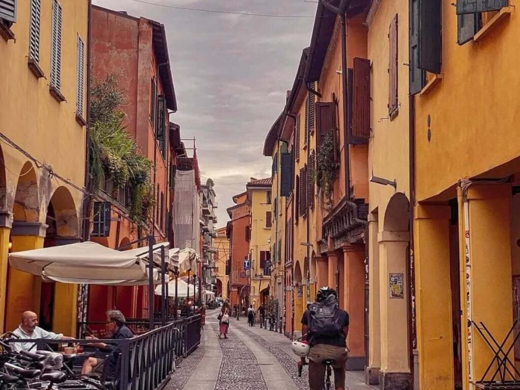 Evening aperitivo scene with people and outdoor tables on Via del Pratello, Bologna