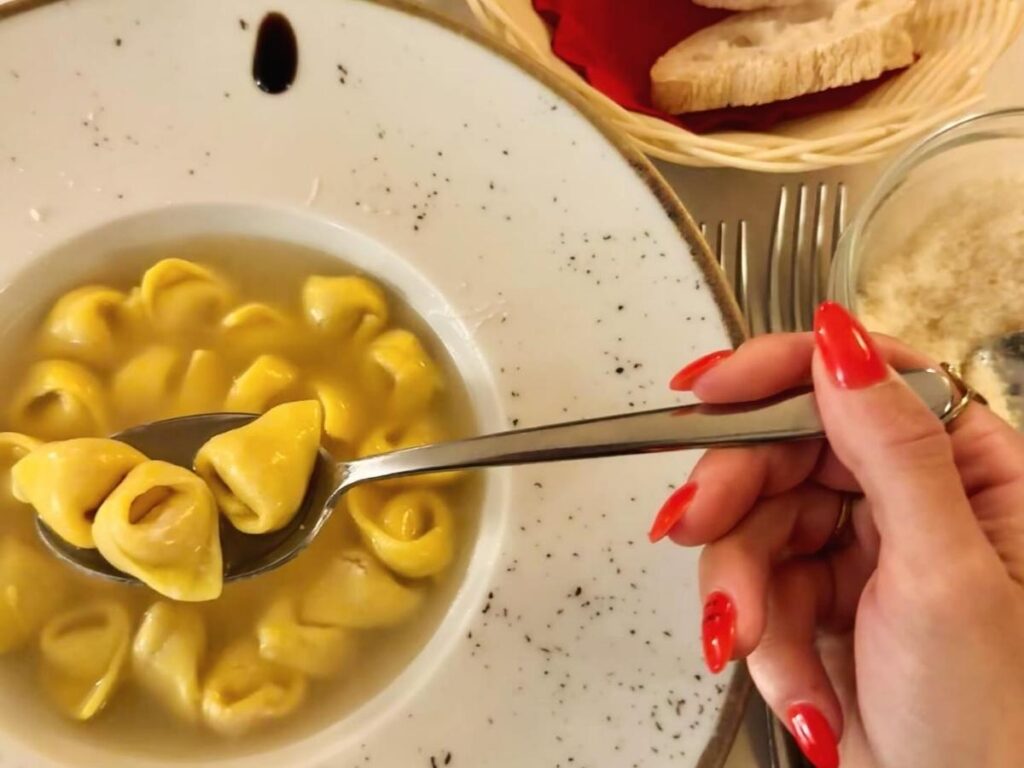 Locals eating tortellini at a small counter in the Quadrilatero Market, Bologna