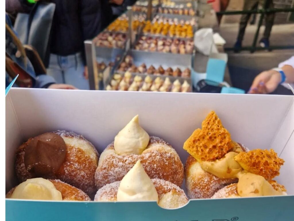 Freshly made doughnuts filled with custard at Bread Ahead stall in Borough Market, London