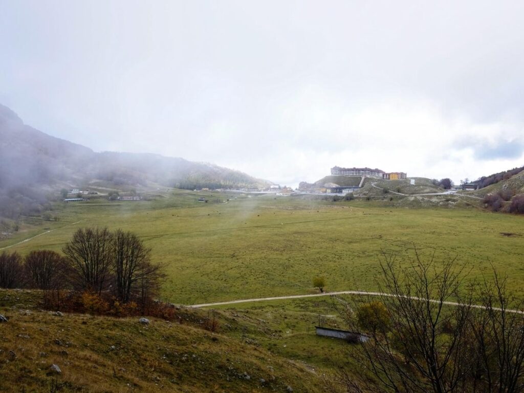 Green summer slopes and wildflowers at Campitello Matese with hiking trails and distant peaks.