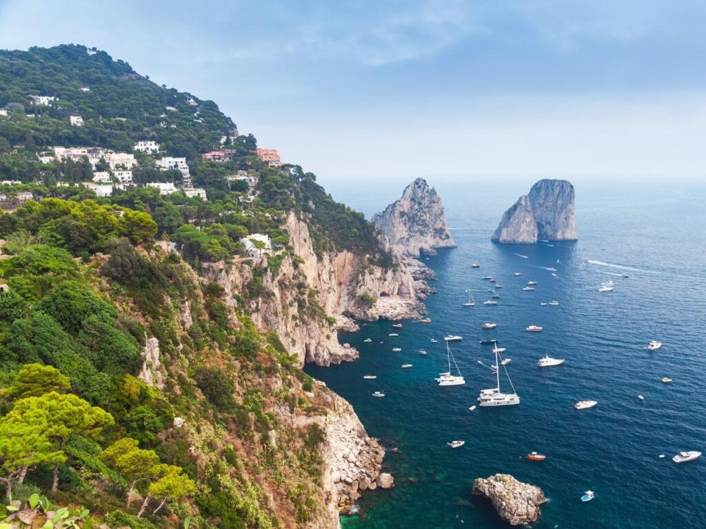 Rowboats entering the Blue Grotto on Capri with turquoise water glowing inside the cave.