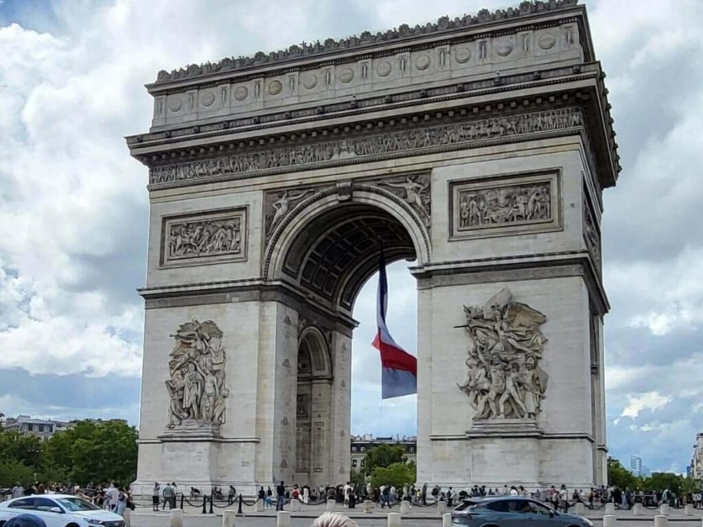 People walking along the Champs-Élysées toward the Arc de Triomphe in Paris
