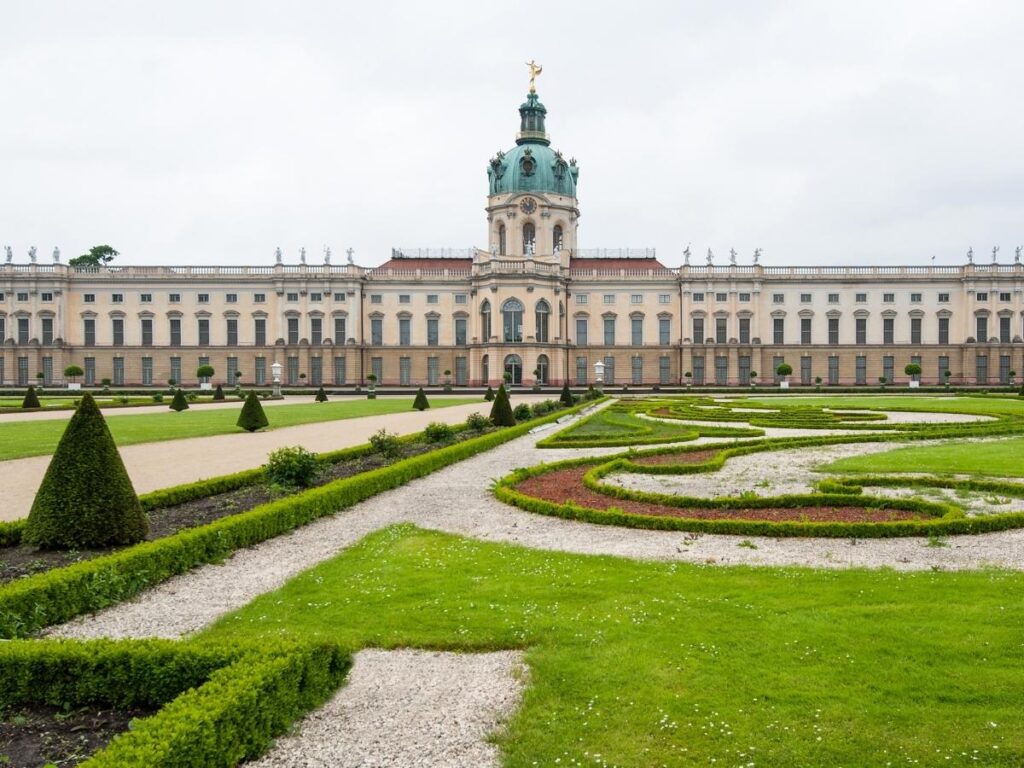 Charlottenburg Palace reflecting in the pond surrounded by green gardens on a sunny day