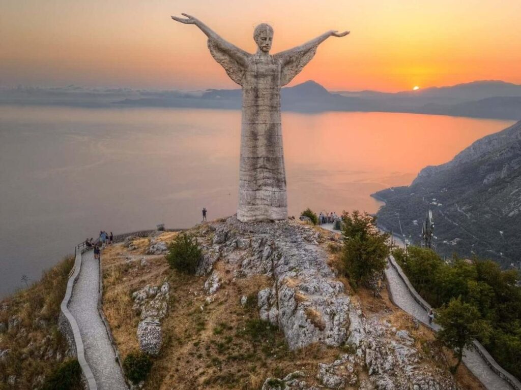 Christ the Redeemer statue on Monte San Biagio with Maratea and the sea below at sunset