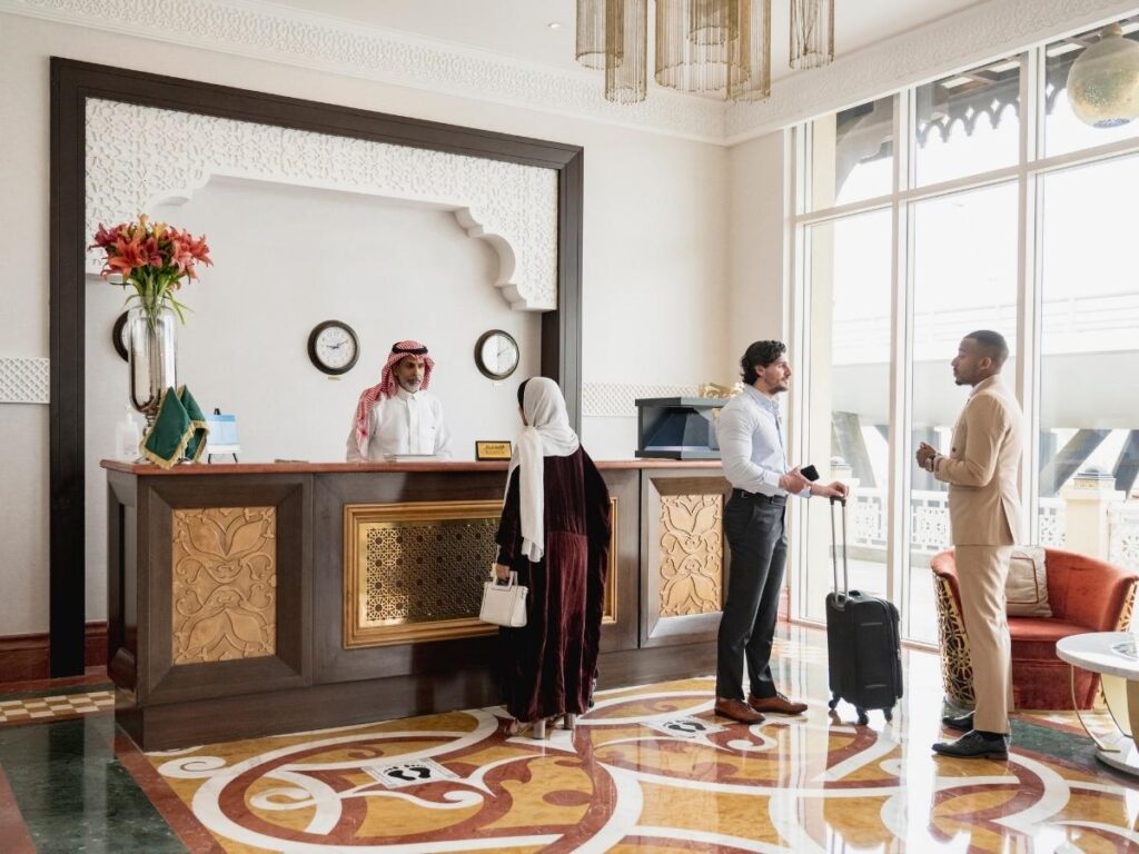 Hotel concierge handing a couple a printed itinerary at a boutique lobby