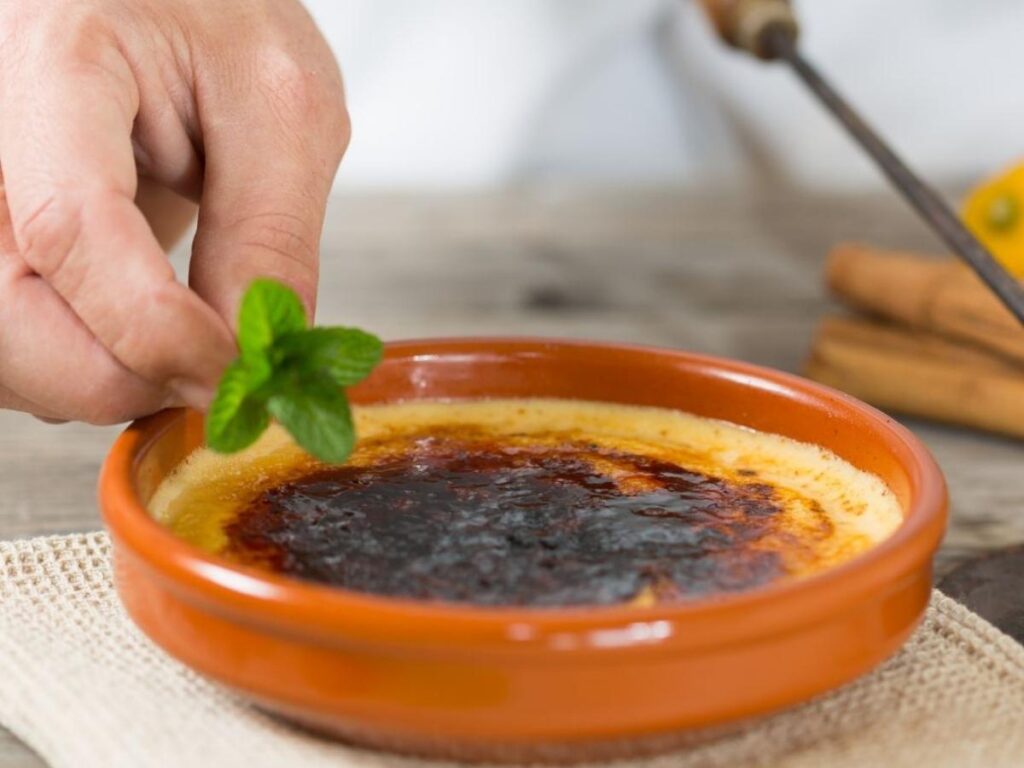Chef caramelizing sugar on crema catalana dessert in Barcelona