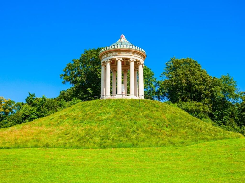 Surfer riding the Eisbach wave in the Englischer Garten with onlookers