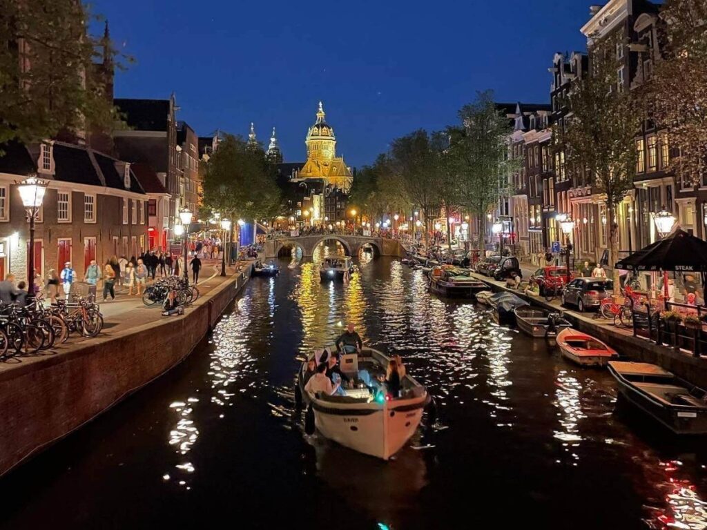 Amsterdam canal at night with bridge lights reflected in the water