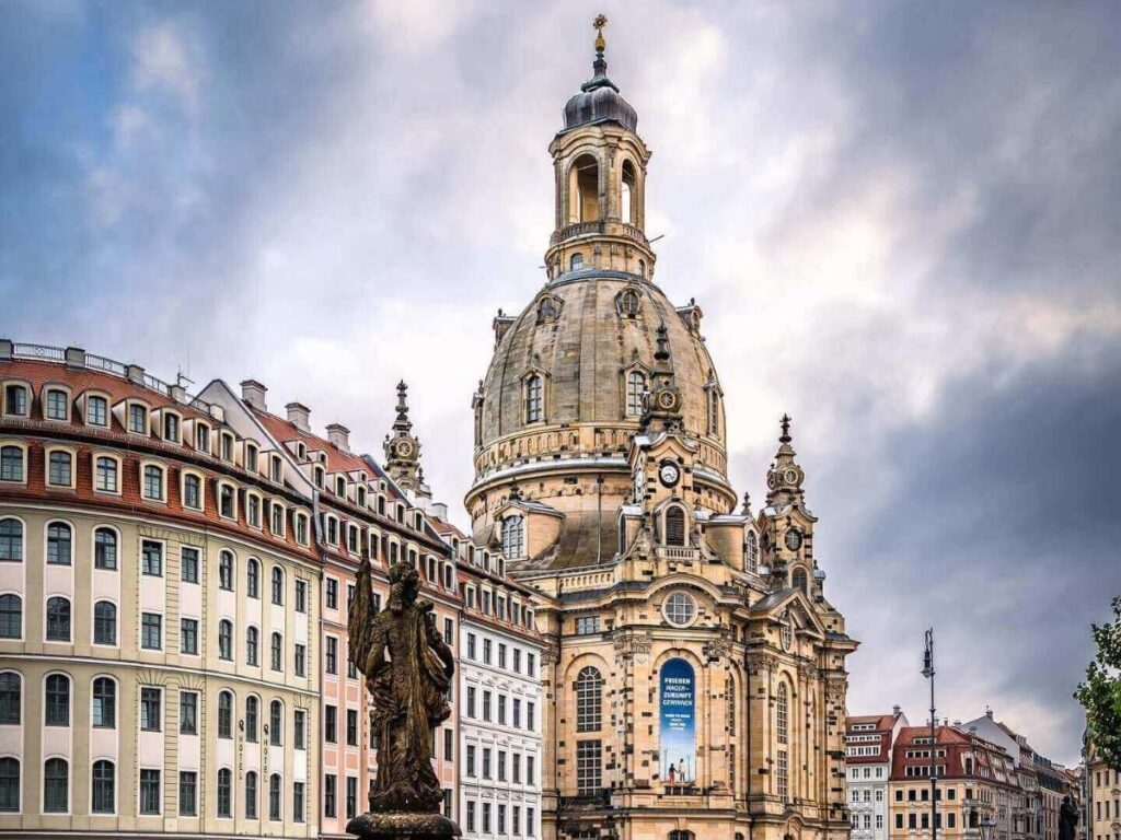 Frauenkirche twin towers rising above Munich rooftops with distant Alps