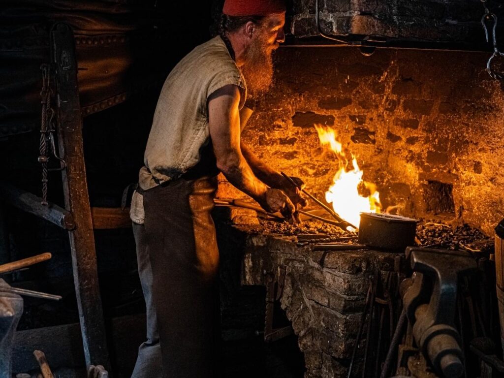 Knife maker hammering a blade on an anvil inside a small workshop in Frosolone.