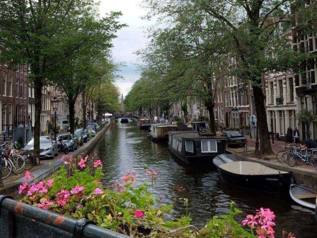 Tourist holding a paper map on a bridge over an Amsterdam canal with cyclists passing by