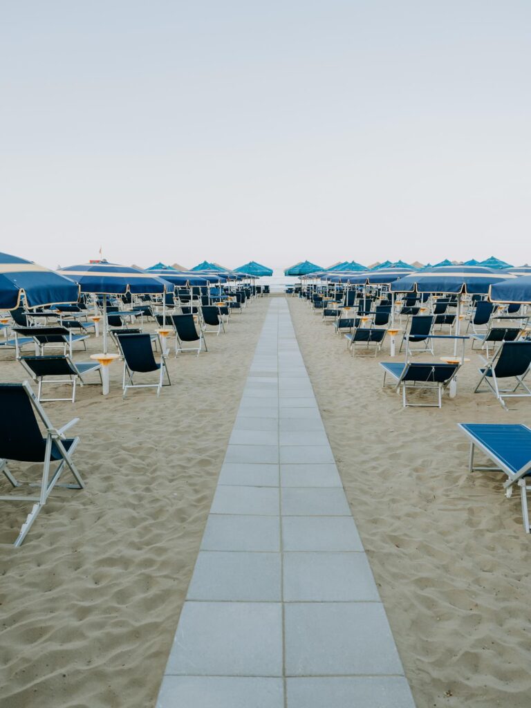 Sandy beach backed by a pinewood near Marina di Petacciato with empty sunbeds in early morning light