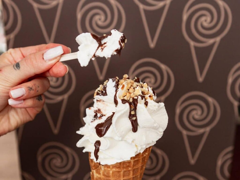 Scoop of pistachio gelato in a cup from Gelateria Marina with Piazza Mazzini blurred behind.