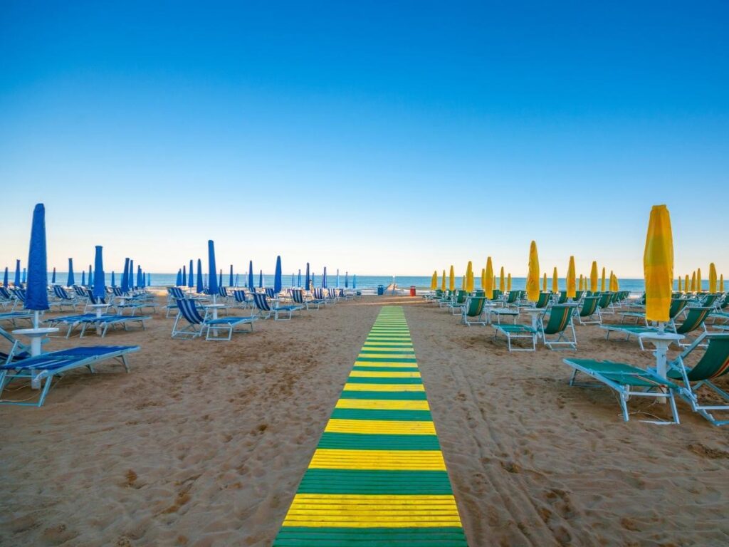Neat rows of colorful umbrellas and loungers along Jesolo’s main beach at midday.”