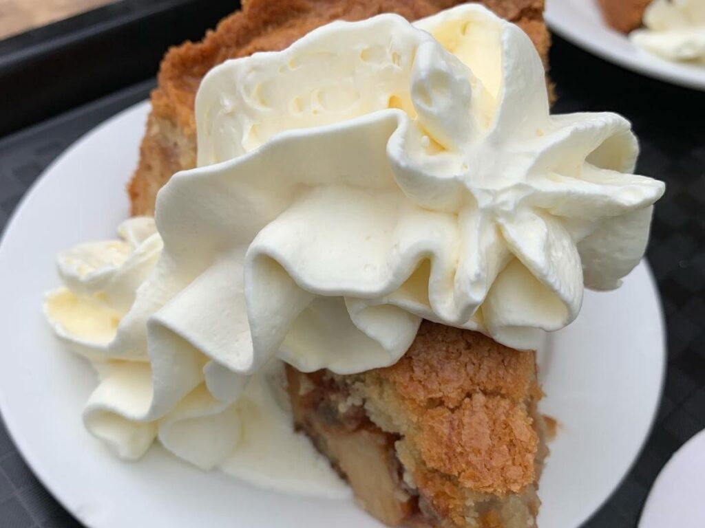 Outdoor tables at Café Winkel 43 with a slice of apple pie on the table and canal houses in the background