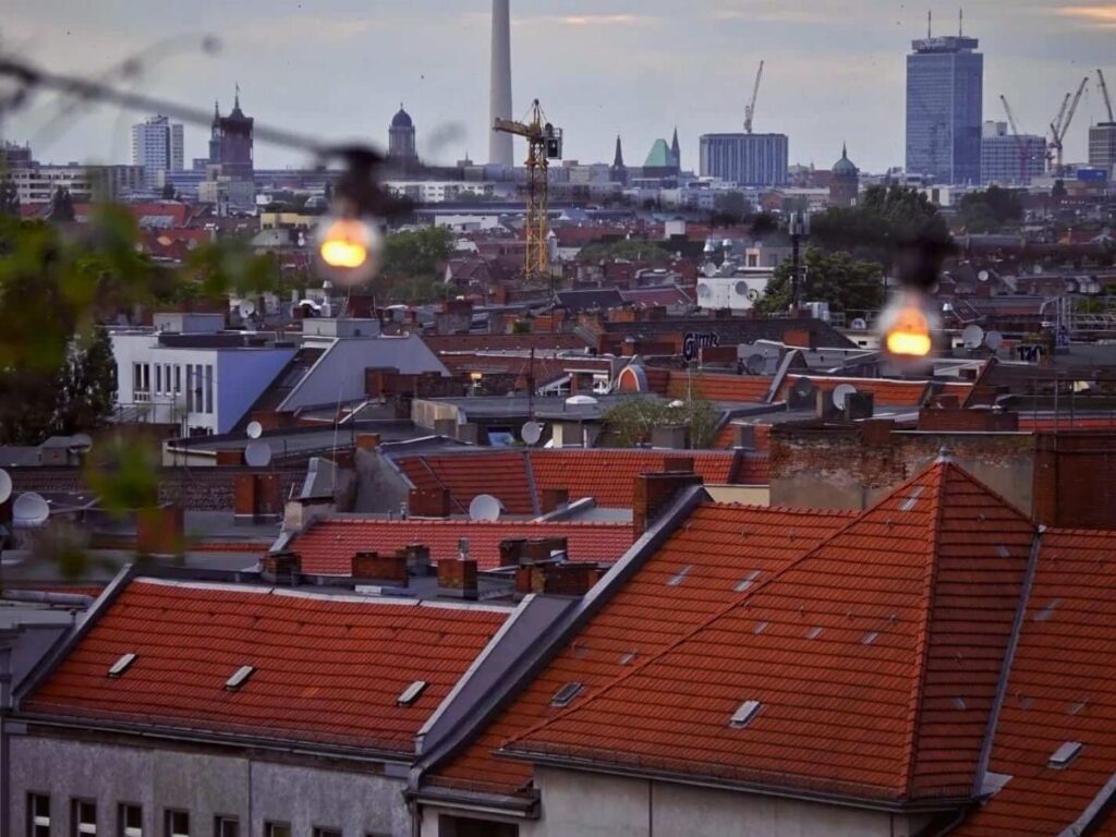 Rooftop bar Klunkerkranich in Neukölln with skyline views and people watching sunset over Berlin.