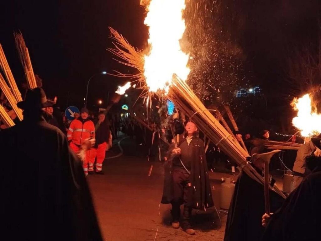 Night scene from La N’docciata in Agnone showing townspeople carrying giant burning torches through a narrow street.