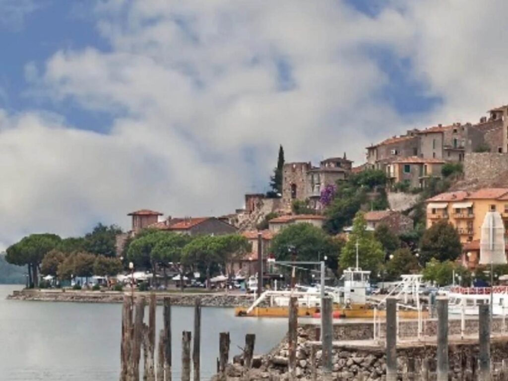 Ferry crossing Lake Trasimeno at sunset with people leaning on the rail and islands in the distance