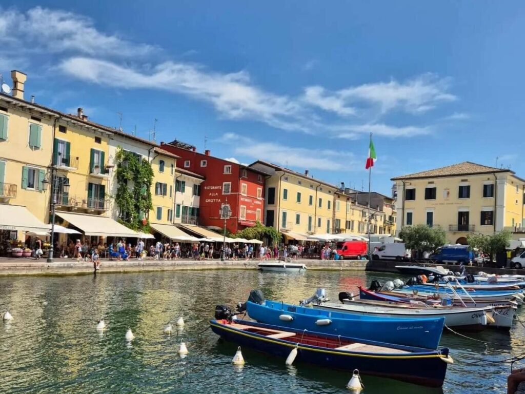 Families and children playing on a pebble beach near Lazise with shallow, calm lake water