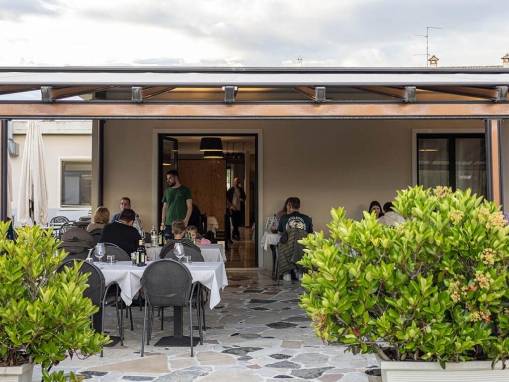 Table set for lunch at a lakeside trattoria in Lazise with wine glasses and Garda fish dishes