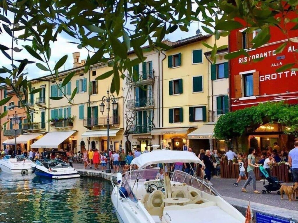 Lazise lungolago promenade with people strolling, benches and lake views toward Bardolino