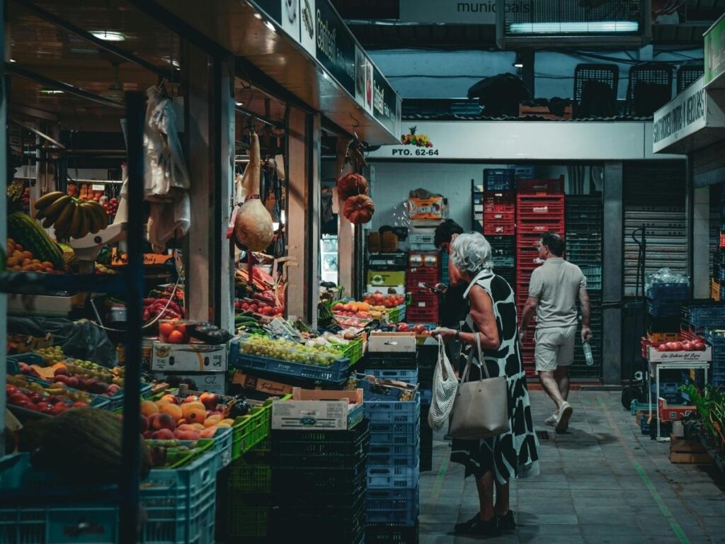 Market stalls in Lazise selling local olive oil, fruit, and handmade ceramics on a sunny morning