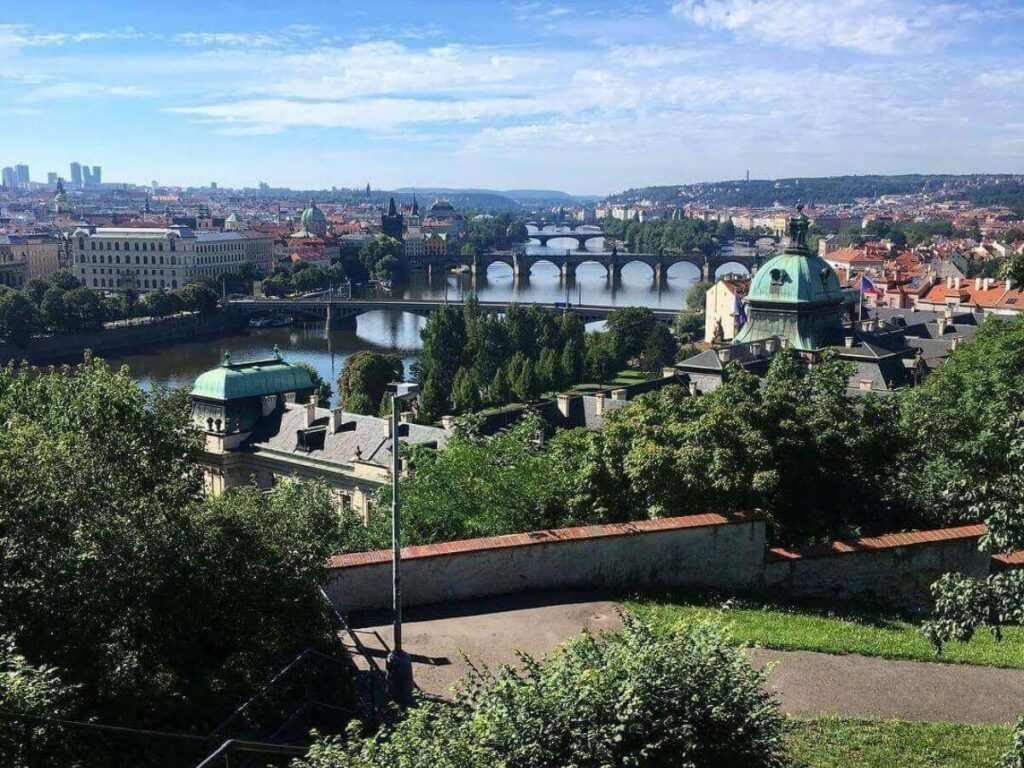 Letná Park terrace at golden hour with people sitting at the beer garden and panoramic view of Prague’s bridges.