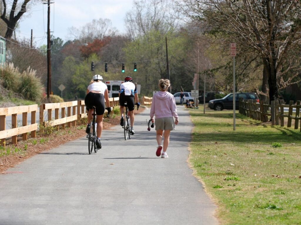 Cyclists on the Lazise to Bardolino lakeside path with clear blue water and mountains in the distance