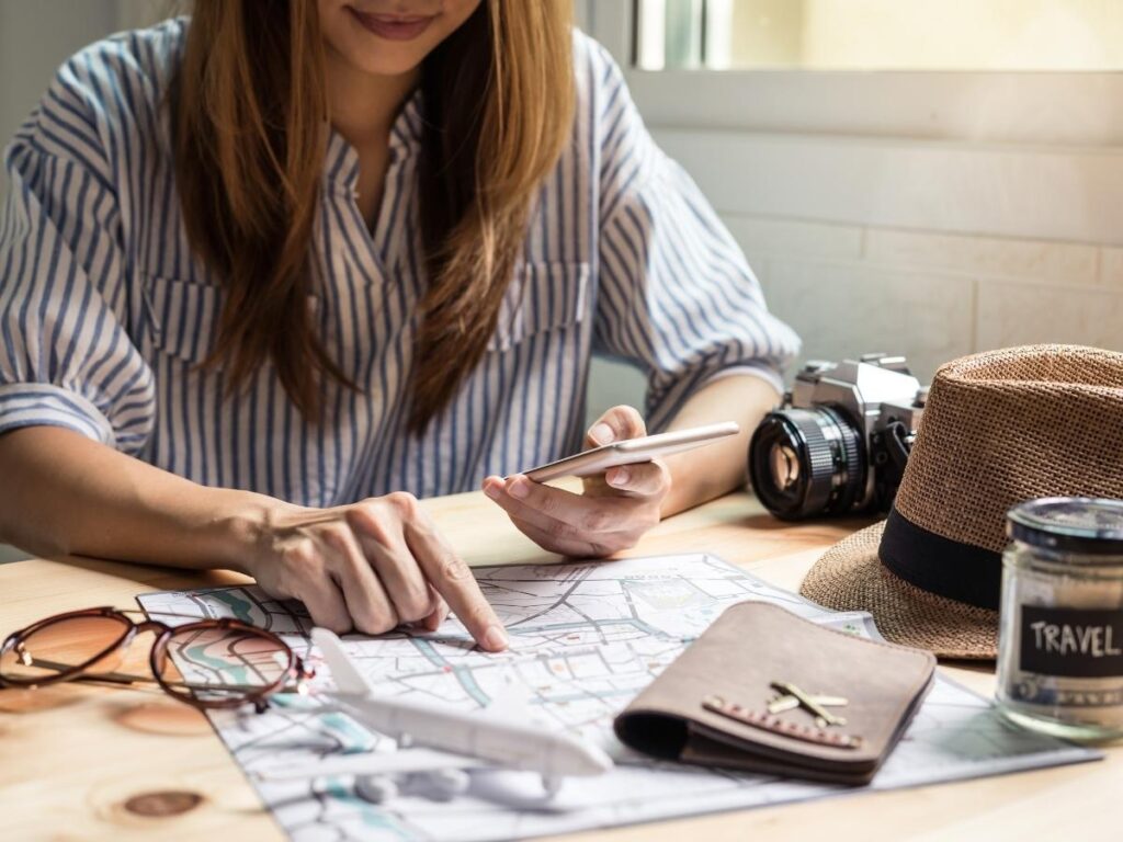 Travel planner, passport, camera, sunglasses on a desk