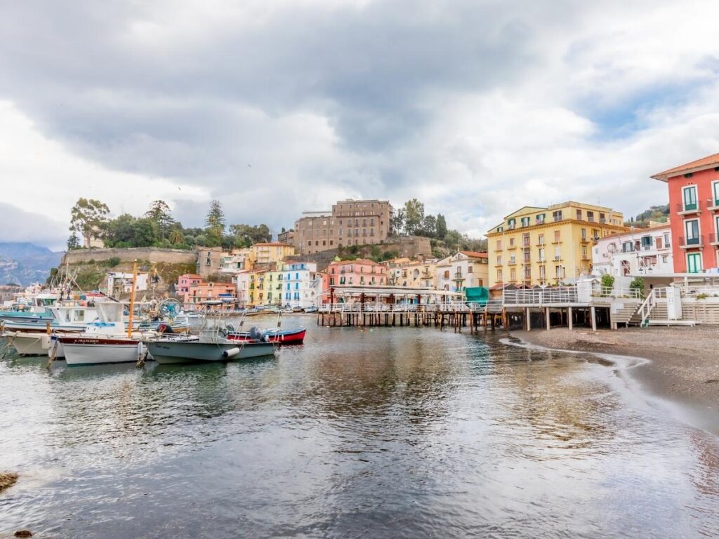 Colorful fishing boats docked at Marina Grande with pastel houses and nets drying in the sun.