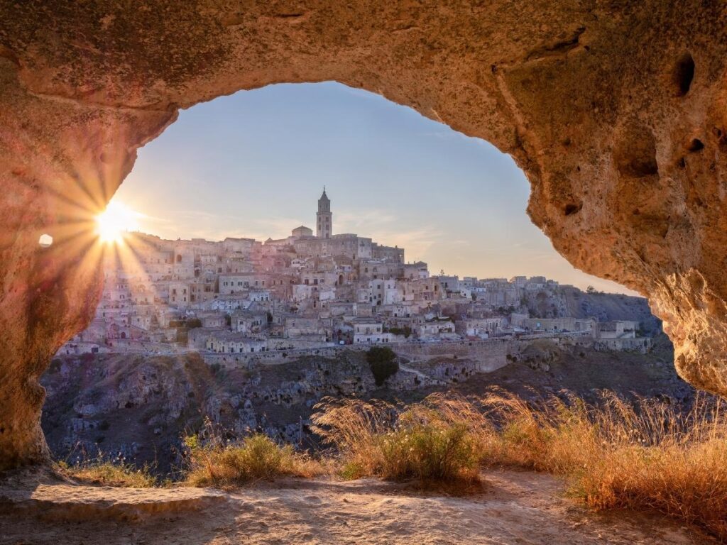View of Matera’s cave dwellings stacked along the hillside, glowing in late afternoon light.