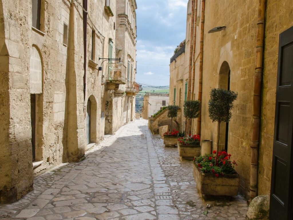 Narrow alley in Sasso Caveoso with ancient stone homes carved into the hillside and soft light filtering through.