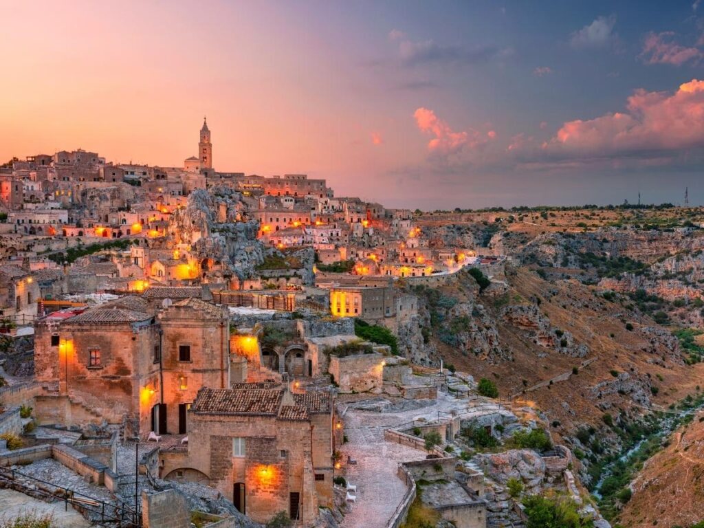 Matera at sunset with warm golden light over the cave dwellings and cathedral tower.