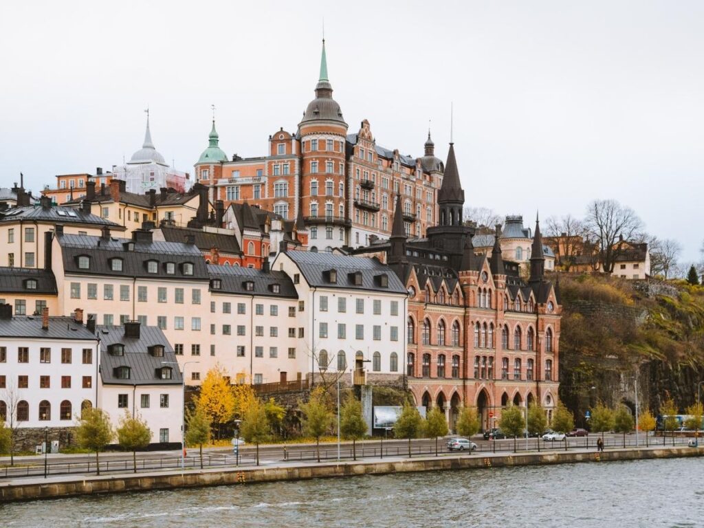Panoramic view from Monteliusvägen across Stockholm rooftops and water at sunset.