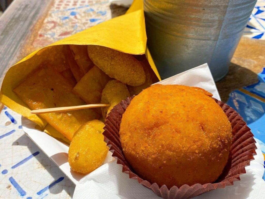 Close-up of freshly fried arancini being opened at a Palermo market stall