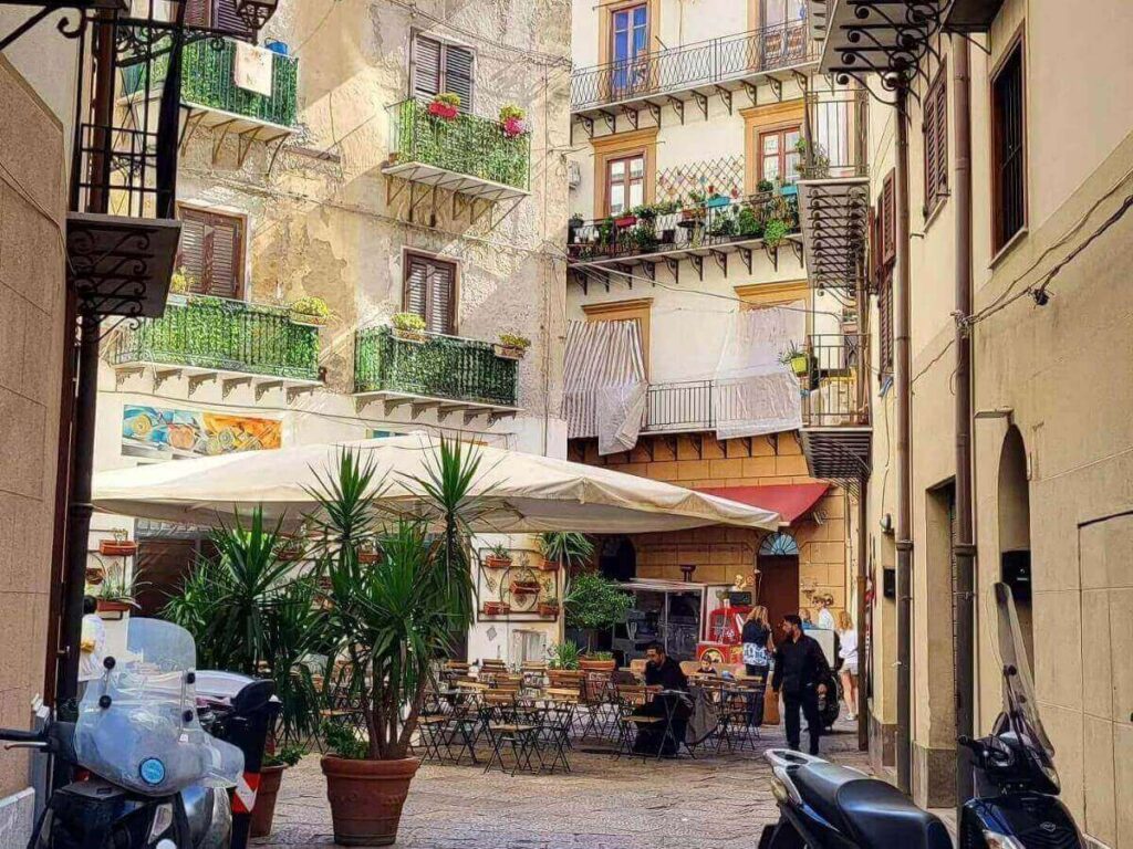 Narrow cobbled street lined with balconies and colorful laundry in Palermo’s historic center